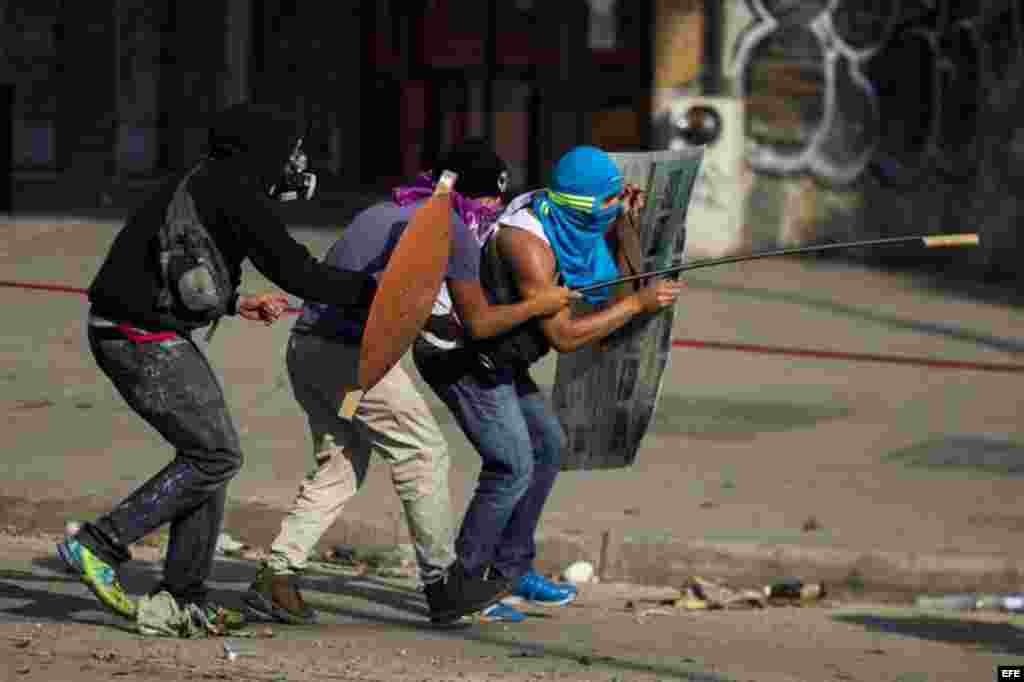 Un grupo de manifestantes se defienden de la policía durante una protesta