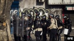 Un grupo de manifestantes se defienden de la policía durante una protesta