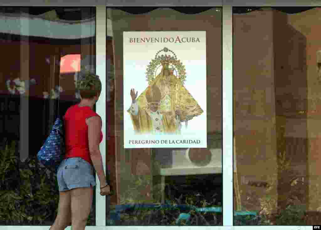 Una mujer observa un cartel de bienvenida al papa Benedicto XVI hoy, lunes 19 de marzo, en La Habana (Cuba). El Pontífice llegará a la isla el próximo día 26 para una visita de tres días.