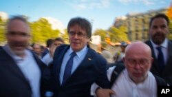 Acompañado por su abogado Gonzalo Boye, segundo a la derecha, Carles Puigdemont, segundo a la izquierda, llega para supuestamente asistir al debate de investidura en Barcelona, España, el jueves 8 de agosto de 2024.. (AP Photo/Emilio Morenatti)