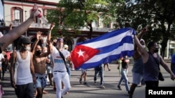 Manifestantes sostienen una bandera cubana durante las protestas del 11 de julio de 2021, en La Habana, Cuba. (REUTERS/Alexandre Meneghini).