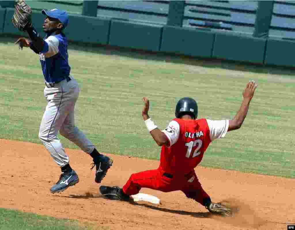 El jugador santiaguero Héctor Olivera (dcha), se desliza quieto en segunda, mientras el segunda base de Industriales, Enrique Diaz (izda) trata de alcanzar la pelota.